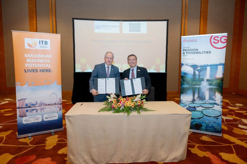 Two professionals holding signed agreements during the ITB Asia event.