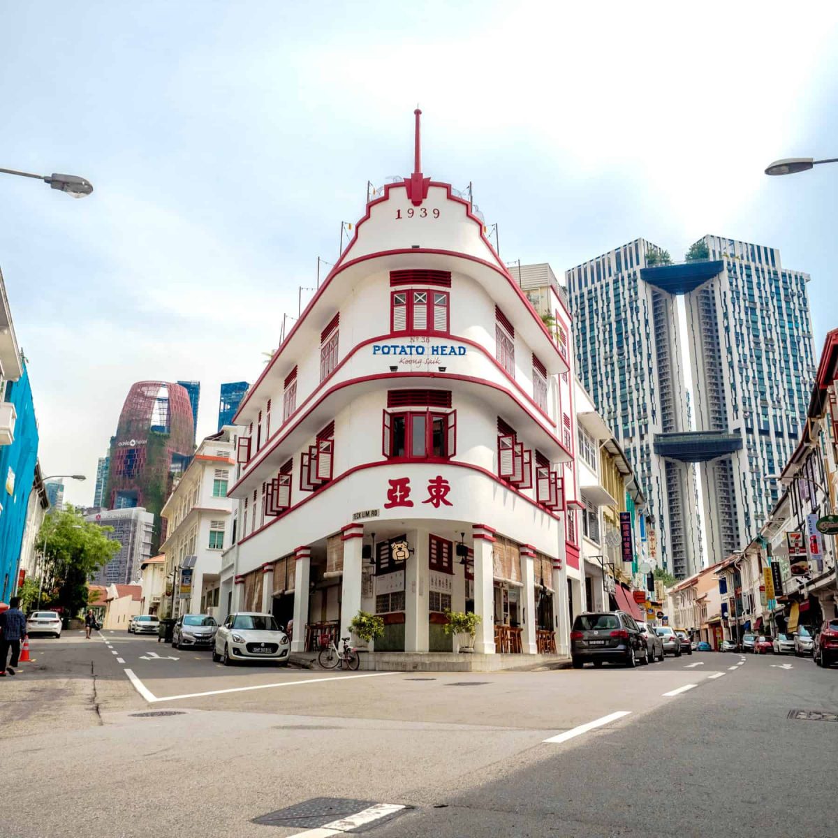 Colorful heritage building with modern cityscape in background, vibrant Singapore street scene.