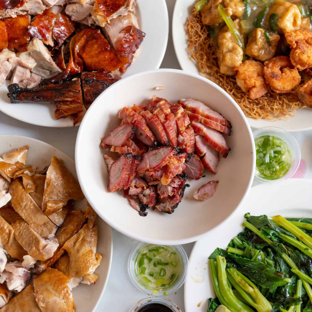 Delicious Chinese BBQ meats and vegetables served on white plates, showcasing Asian cuisine at its finest.