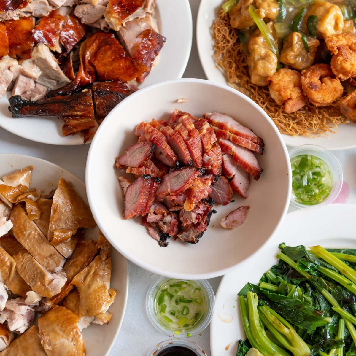 Delicious Chinese BBQ meats and vegetables served on white plates, showcasing Asian cuisine at its finest.