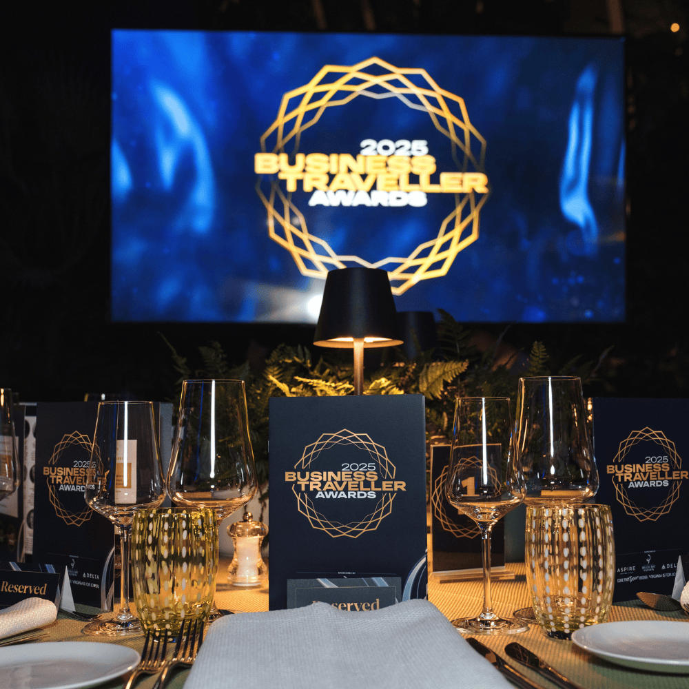 Business Traveller Awards 2025 event setup with tableware and a large screen.