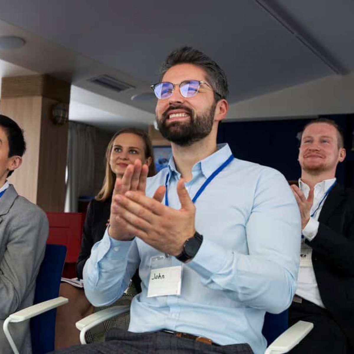 Smiling business professionals applauding at ITB Asia 2026 travel trade show in Singapore.